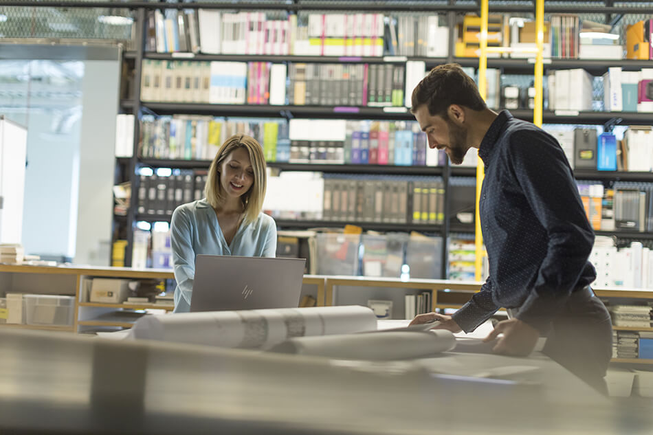 man and woman working at table with printed documents from production printers